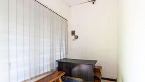 A small room with a wooden bench, a desk, and a window with blinds. - SPOT ON 91521 Mayong Guesthouse (Mayong)