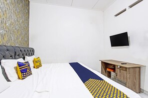 Habitación de hotel con cama, un escritorio de madera y un televisor montado en la pared.