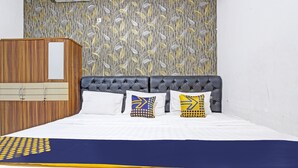 A neatly made bed with a blue and yellow bedspread, a tufted headboard, and patterned pillows. - SPOT ON 91521 Mayong Guesthouse (Mayong)