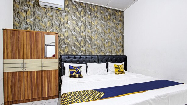 A bedroom with a bed, a wardrobe, and a wall-mounted air conditioner. - SPOT ON 91521 Mayong Guesthouse (Mayong)