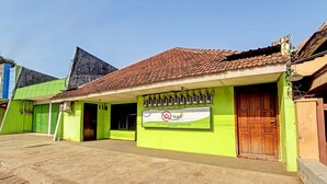 A building with a green facade, a tiled roof, and a signboard. - SPOT ON 91521 Mayong Guesthouse (Mayong)
