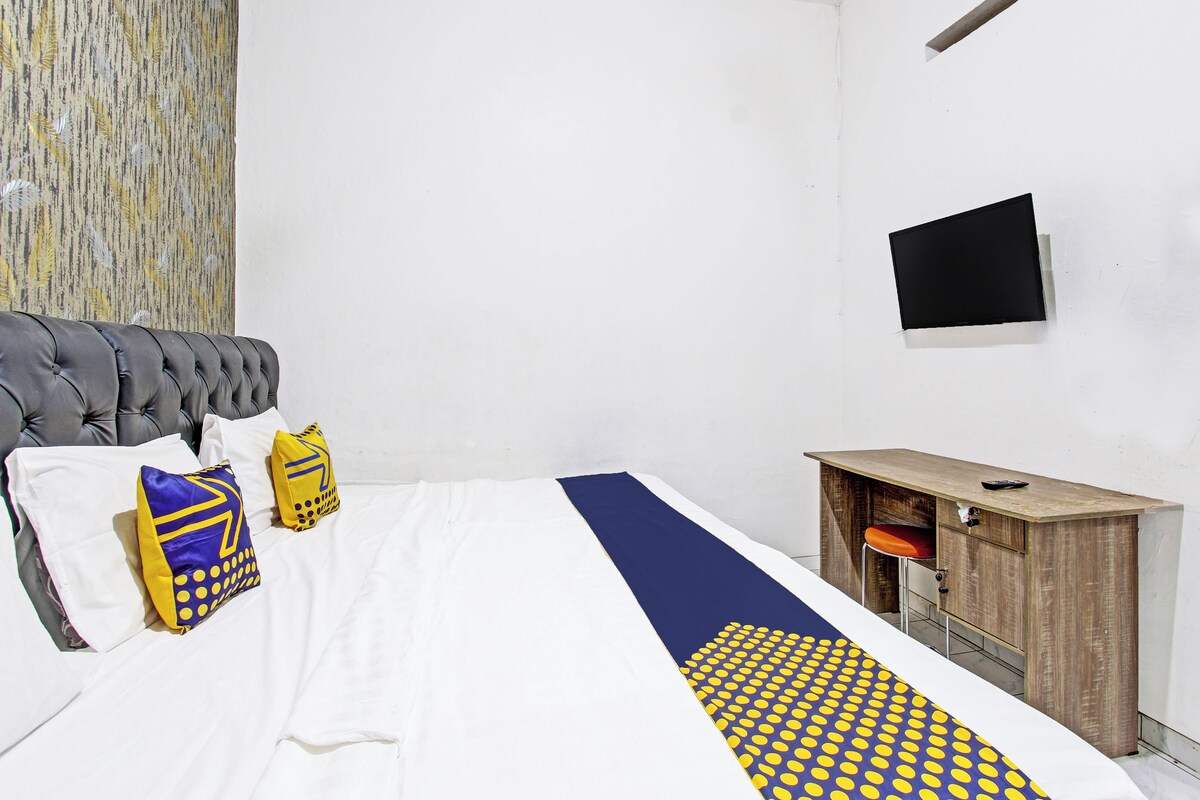 Un dormitorio con cama, televisor en la pared, escritorio de madera y un corredor con diseño.