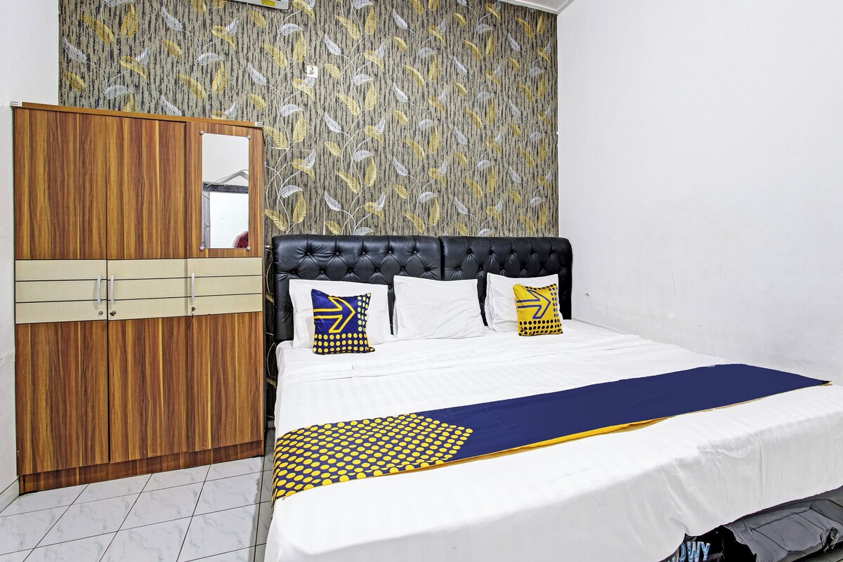 A bedroom with a bed, a wardrobe, and a patterned wall.