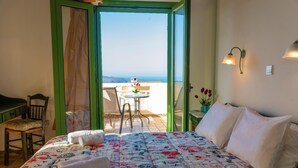Ein Schlafzimmer mit Bett, Stuhl, Tisch und Meerblick.