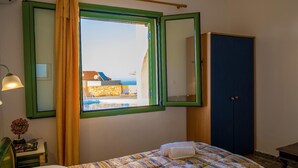 Ein Schlafzimmer mit Bett, einem fenster mit Vorhängen, einem Spiegel, einem Kleiderschrank und einer Lampe.