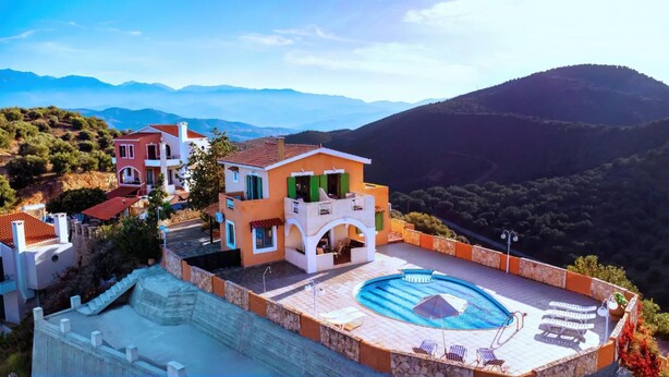 Eine moderne Villa mit Dachpool, umgeben von üppiger Vegetation und Bergen.