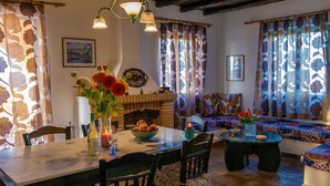Ein gemütliches Wohnzimmer mit Kamin, Esstisch und Sofagarnitur.