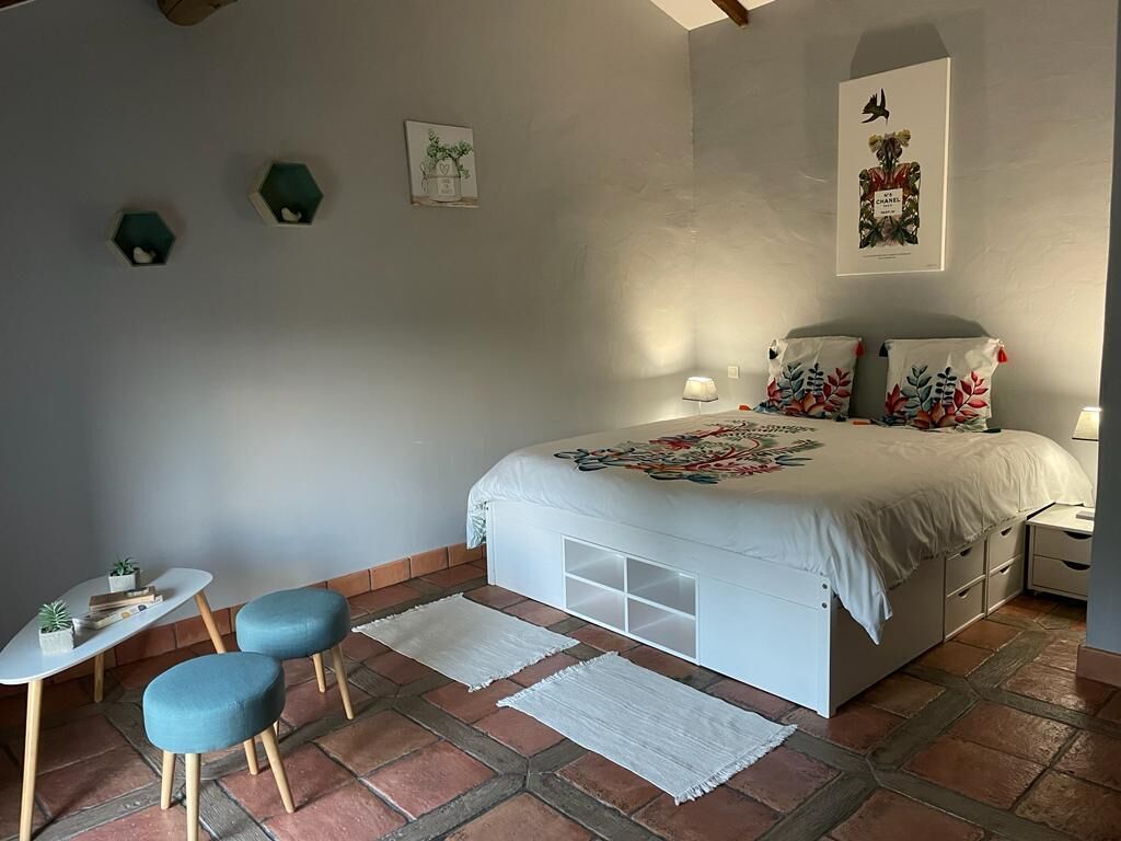 A bedroom with a bed, bedside tables, a small table with chairs, and decorative wall art.