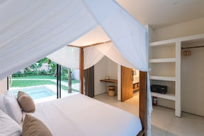 A bedroom with a canopy bed, a view of a swimming pool, and a built-in shelving unit. - Sealuna Villas (Tabanan)