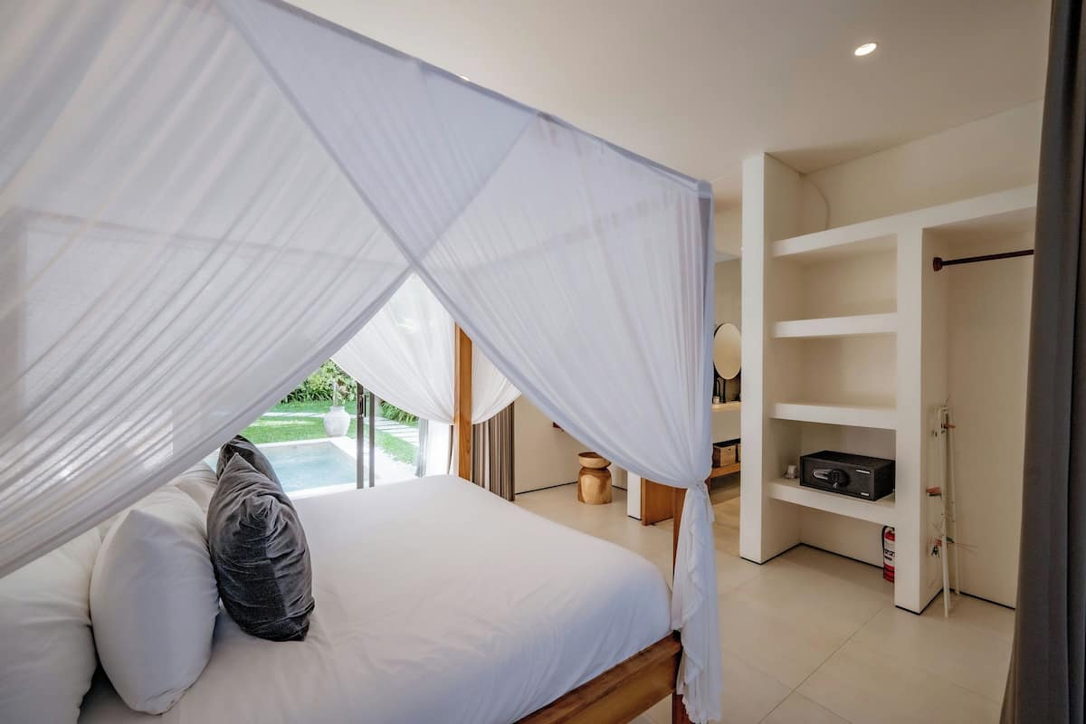 Une chambre avec un lit à baldaquin, une vue sur une piscine et un dressing.