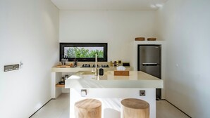 A modern kitchen with a central island, stainless steel appliances, and a large window. - Sealuna Villas (Tabanan)