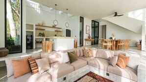 A spacious living area with a large L-shaped sofa, a dining table, and a kitchen in the background. - Sealuna Villas (Tabanan)