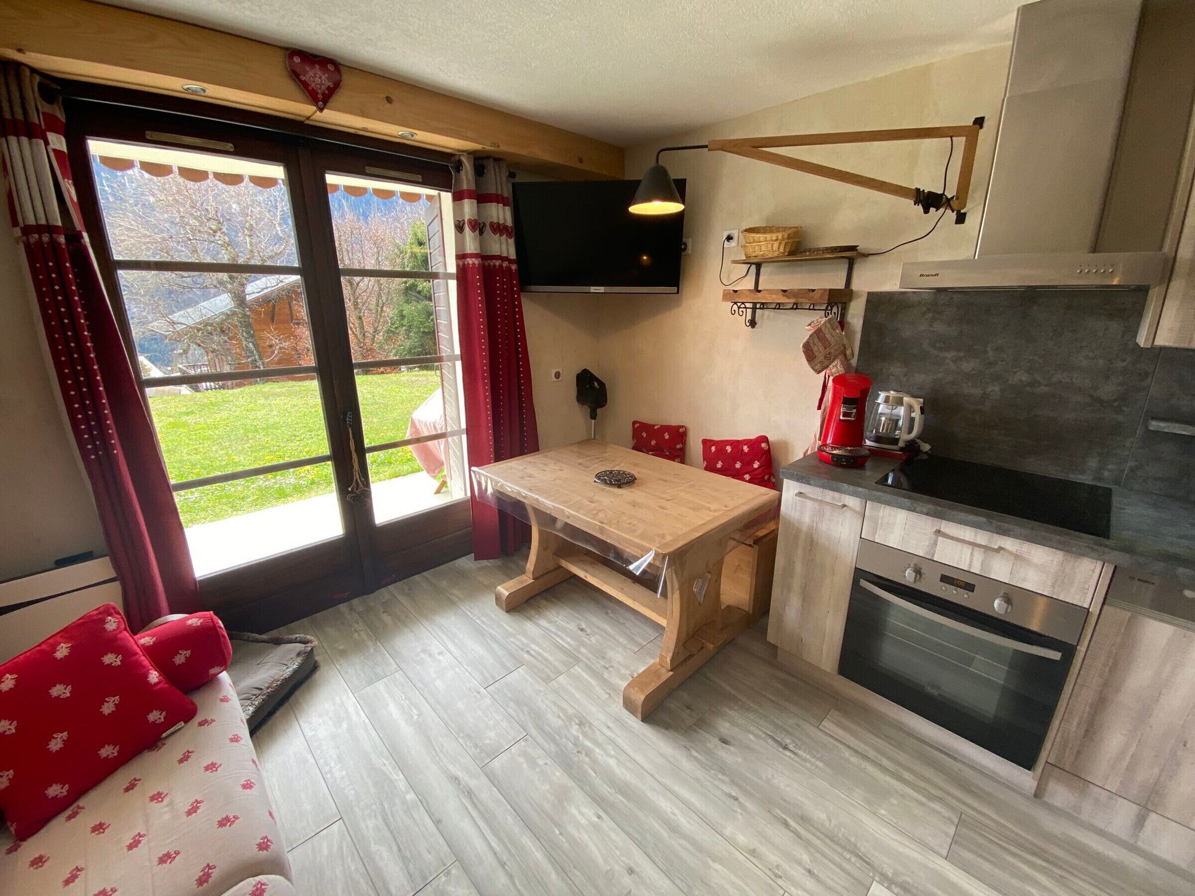 A compact kitchen with a wooden table, a built-in oven, and a TV mounted above it.