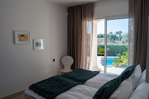 A bedroom with a bed, a chair, and a view of a swimming pool and greenery. - Large Fantastic House With a Garden, a Pool and Beautiful Views (Vence)