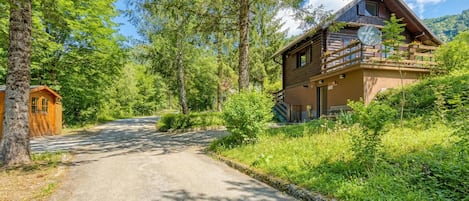 A log cabin with a balcony, surrounded by forest.