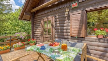 A wooden cabin with a table set for breakfast, surrounded by potted plants.