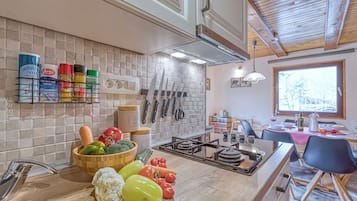 A kitchen with a tiled backsplash, a gas stove, and various kitchen utensils.