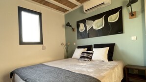 Een slaapkamer met een bed, een raam, een airconditioner en een wandlamp.