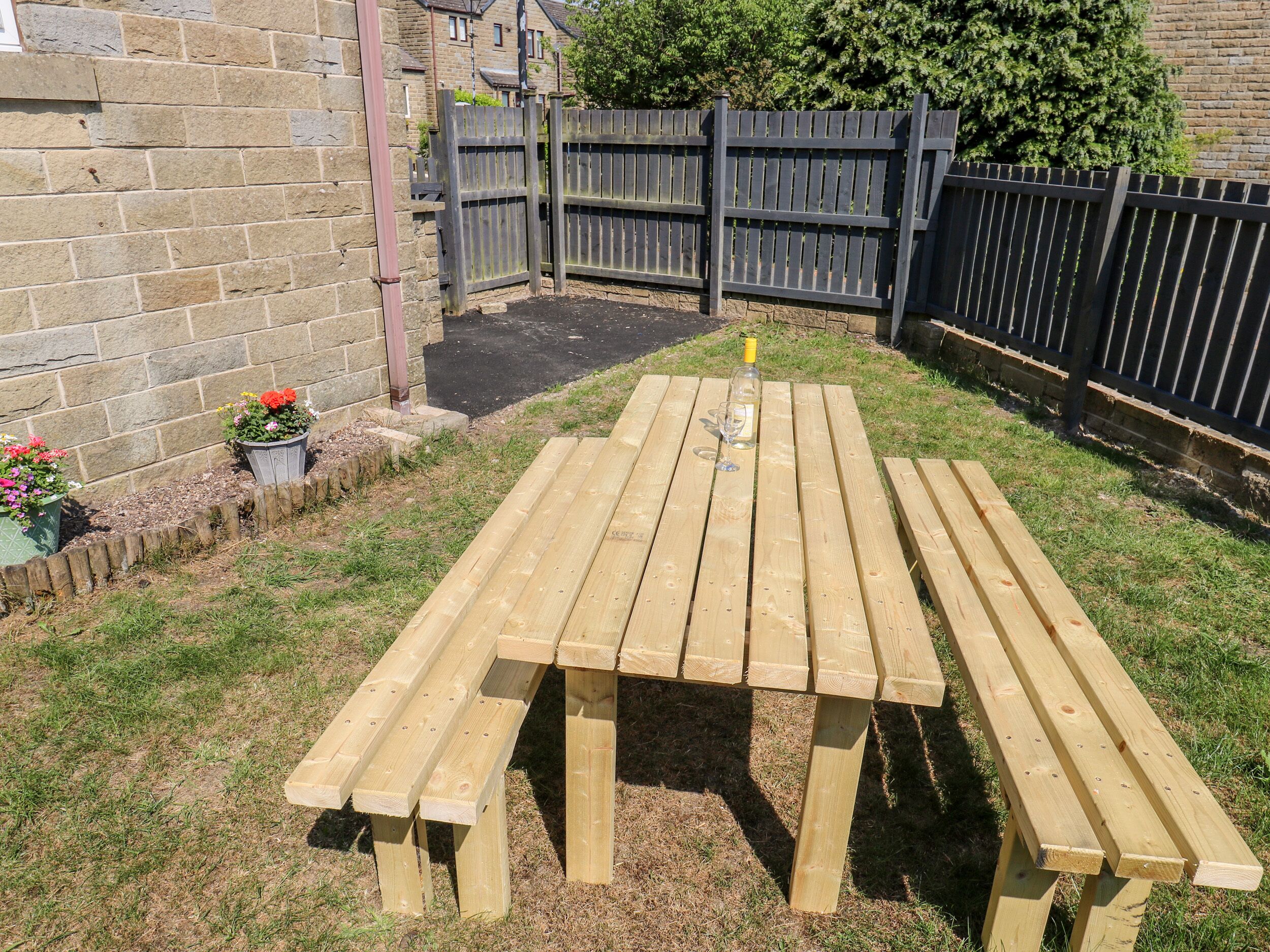 Une table de pique-nique en bois avec des bancs, située dans un jardin.