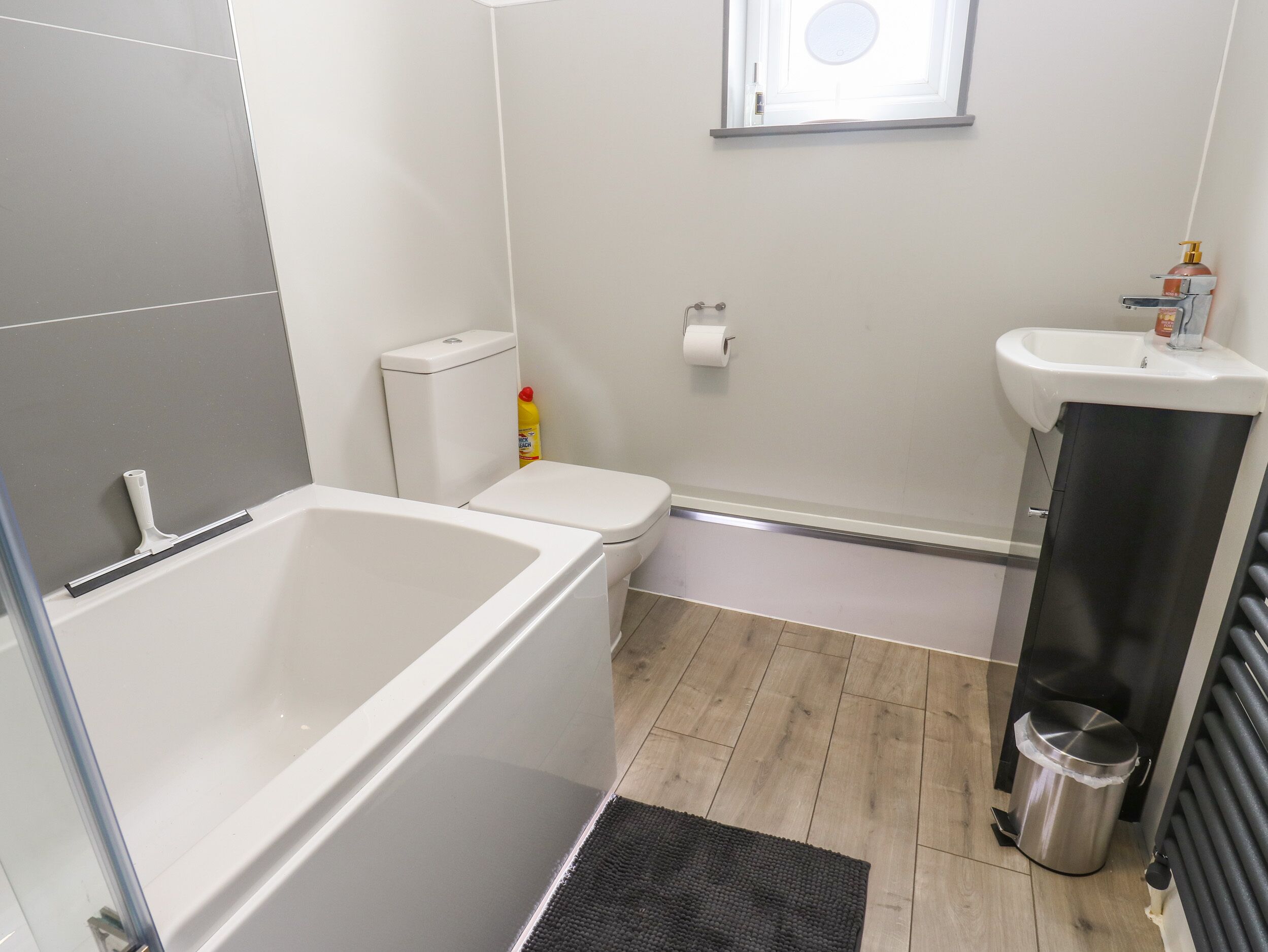 Een badkamer met een bad, toilet, wastafel en een prullenbak.