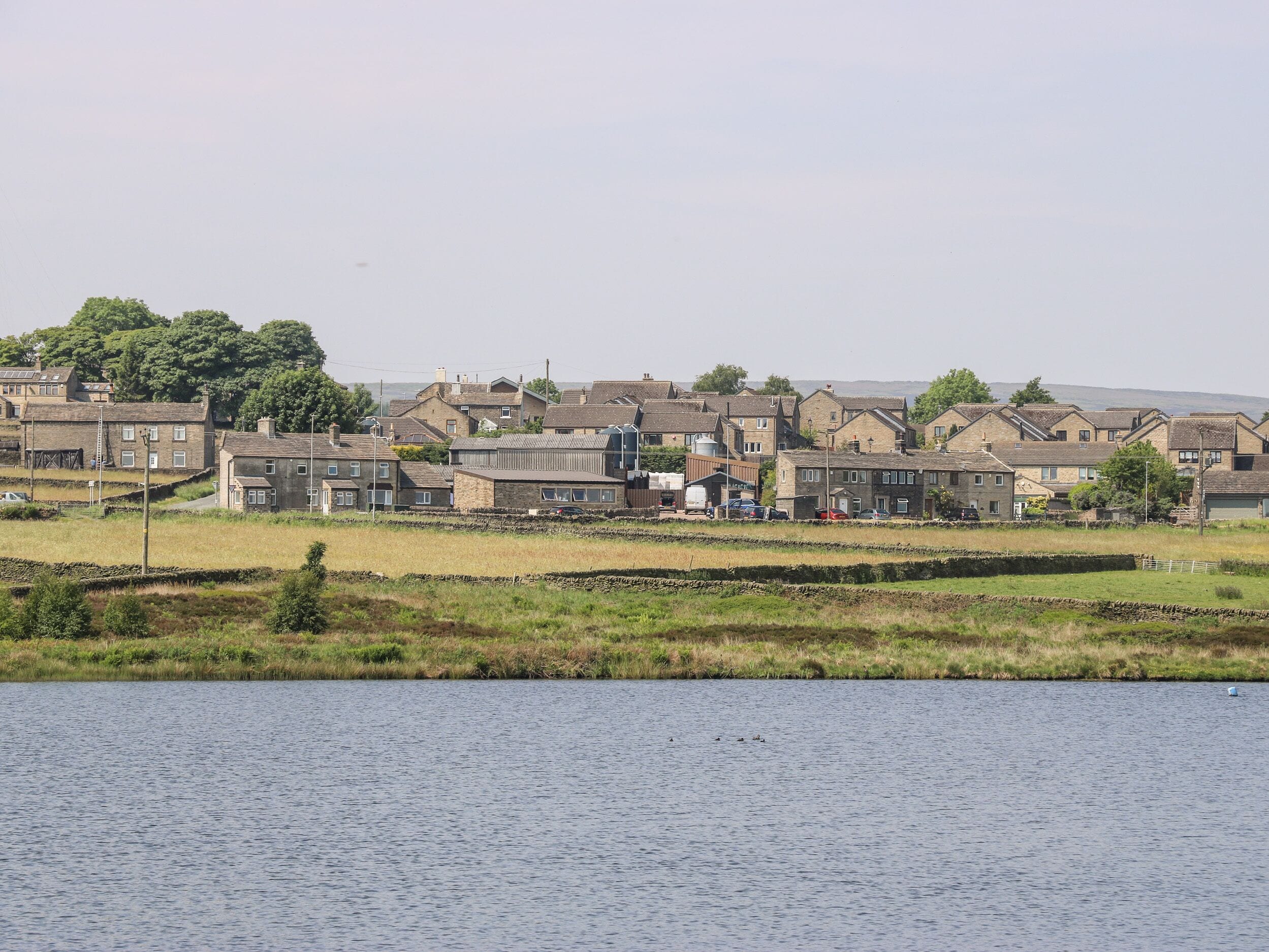 Un village riverain doté de maisons traditionnelles, d’un pont et bordé par un plan d’eau.