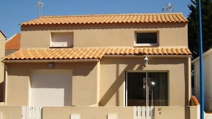 Un bâtiment à deux étages, doté d’un toit recouvert de tuiles, d’une porte de garage et d’une petite fenêtre.