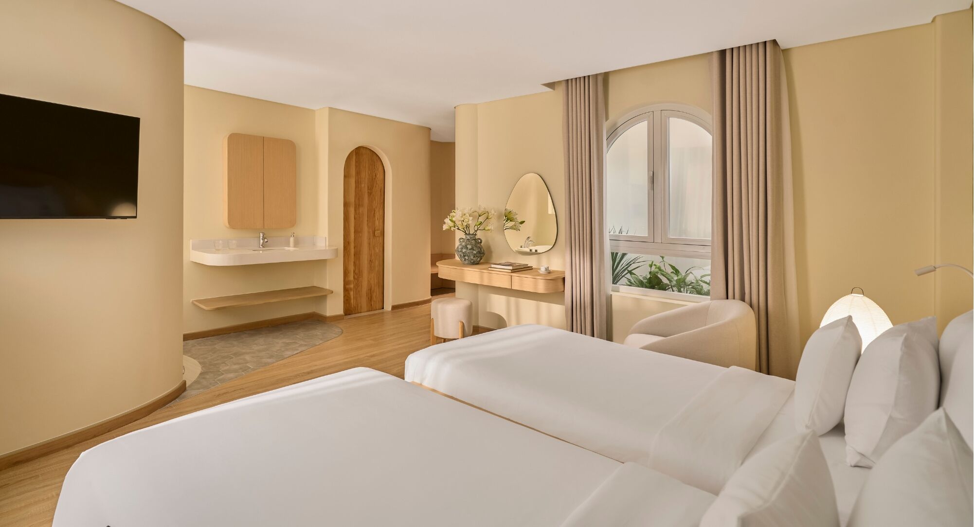 Une chambre d’hôtel avec un lit, un bureau, une télévision, une fenêtre avec des rideaux et un miroir.