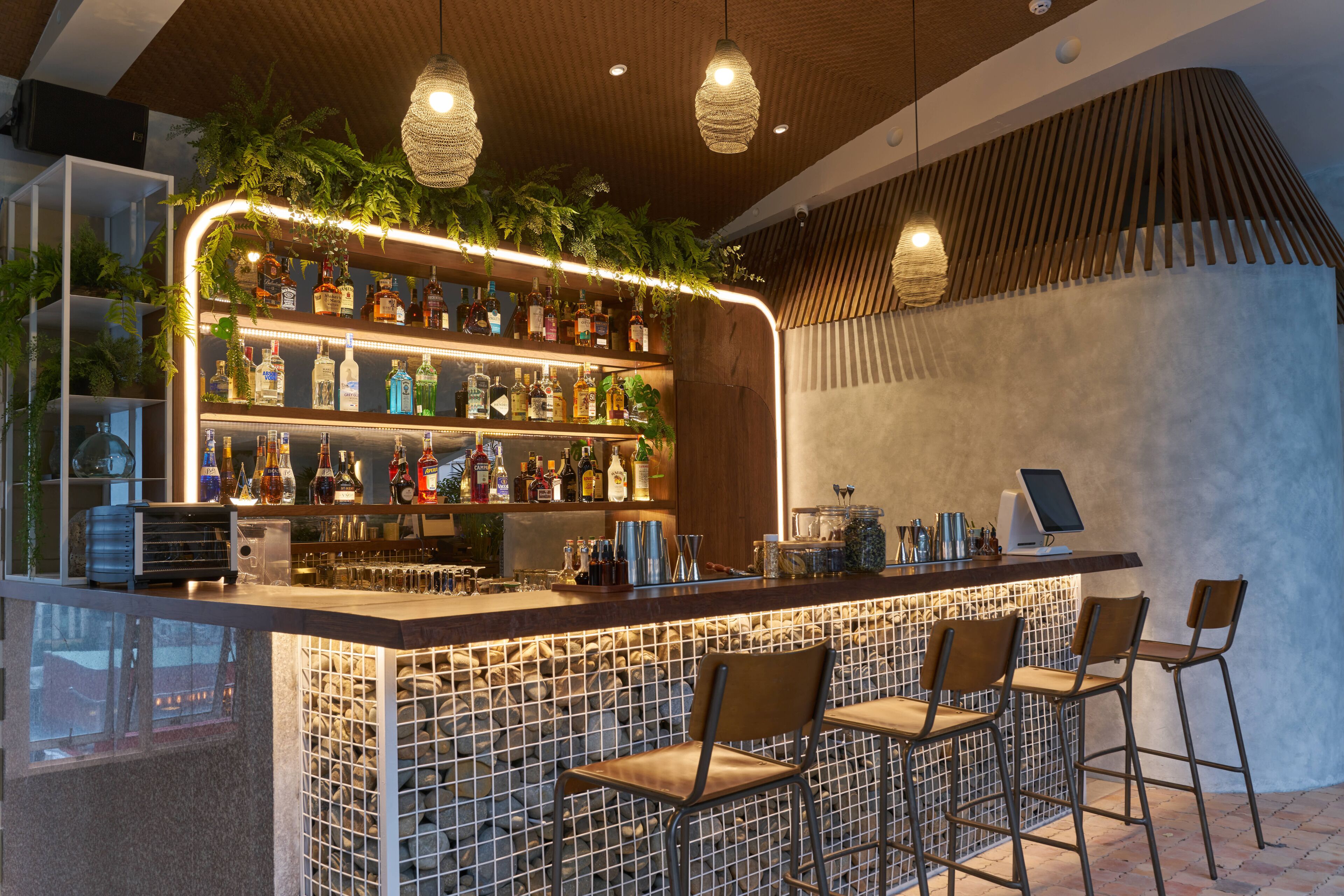 Una zona de bar con techo de madera, luces colgantes y mostrador con taburetes.