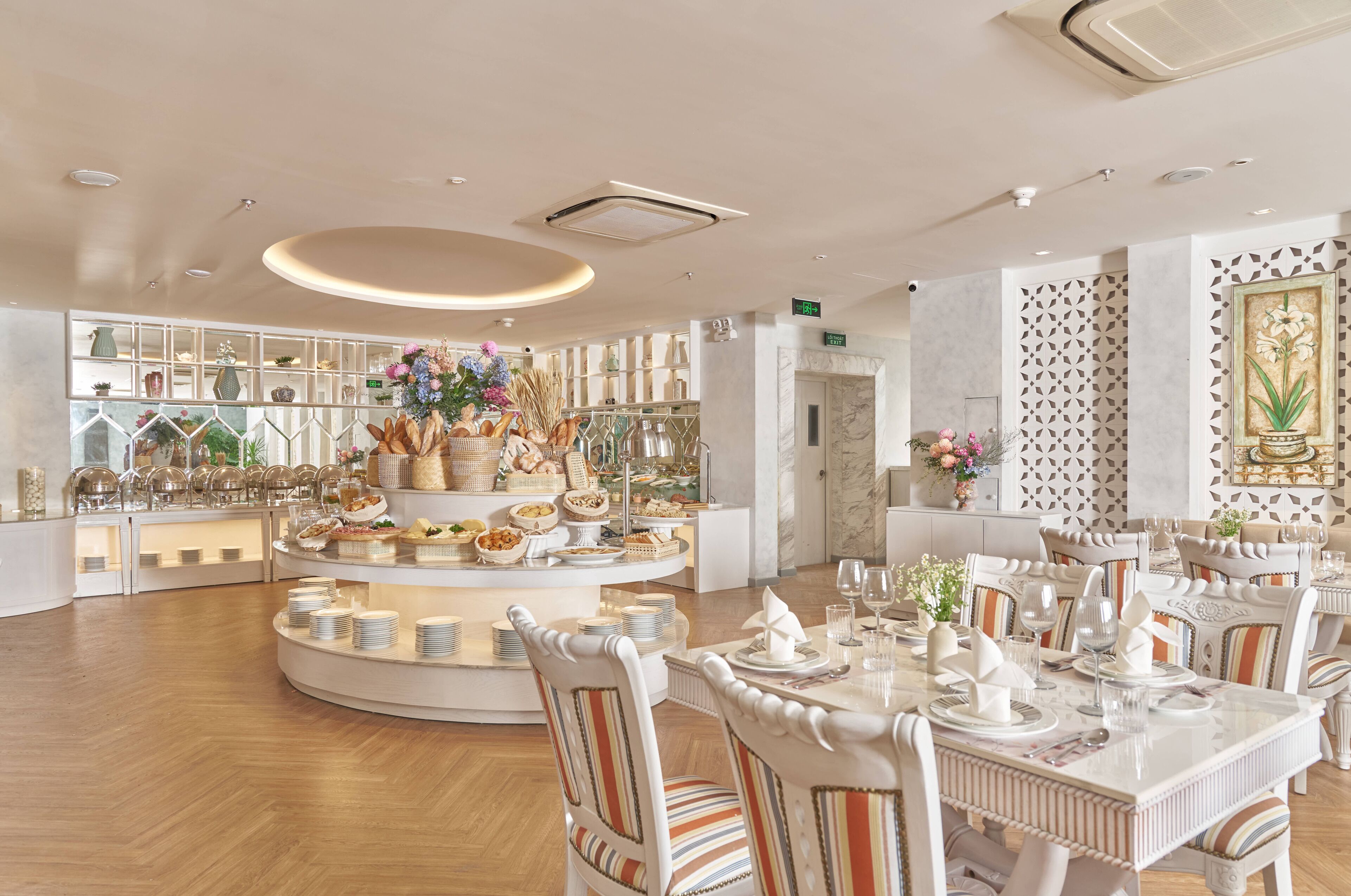 A hotel dining area with a buffet setup, multiple dining tables, and chairs.