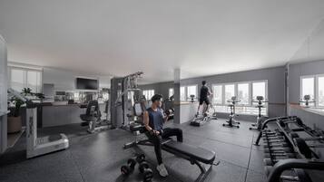 A gym with various exercise equipment, a bench, dumbbells, and a treadmill.