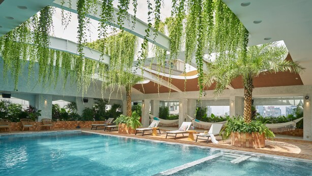 An indoor swimming pool with lounge chairs and hanging plants. - Silverland Mây Hotel (Ho Chi Minh City)