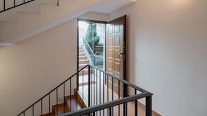 Eine Treppe mit schwarzer Handlauf, die zu einer Tür führt, die in einen Garten hineinmündet.