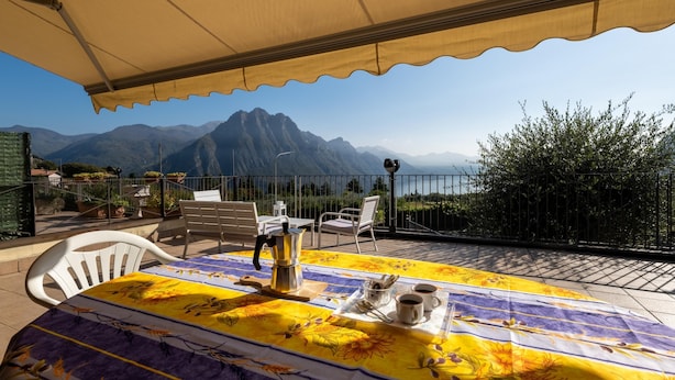 Eine Terrasse mit einem für zwei Personen gedeckten Tisch, einer Kaffeekanne und einer Schale mit Tassen und Zucker.