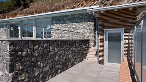 Ein modernes Gebäude mit Natursteinfassade, einem Glasbalkon und einer Holzeingangstür.