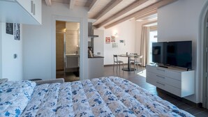 Ein Schlafzimmer mit Bett, Fernseher und einer Essecke mit Stühlen und Tisch.