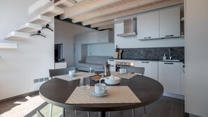 Eine moderne Küche mit weißen Schränken, einer schwarzen Arbeitsplatte und einem Essbereich mit rundem Tisch und Stühlen.