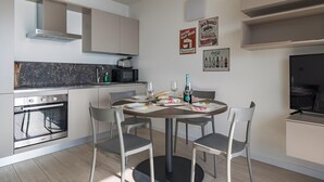 Eine moderne Küche mit Essbereich, ausgestattet mit einem runden Tisch und Stühlen, einem eingebauten Backofen, einer Mikrowelle und einem Herd.