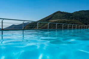 Une piscine à l’eau d’un bleu cristallin, avec des rampes en métal et un paysage montagneux en toile de fond.