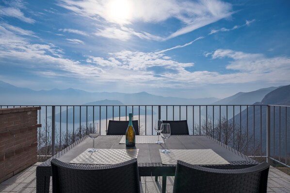 Une terrasse avec une table dressée pour deux personnes, offrant une vue sur un paysage montagneux.