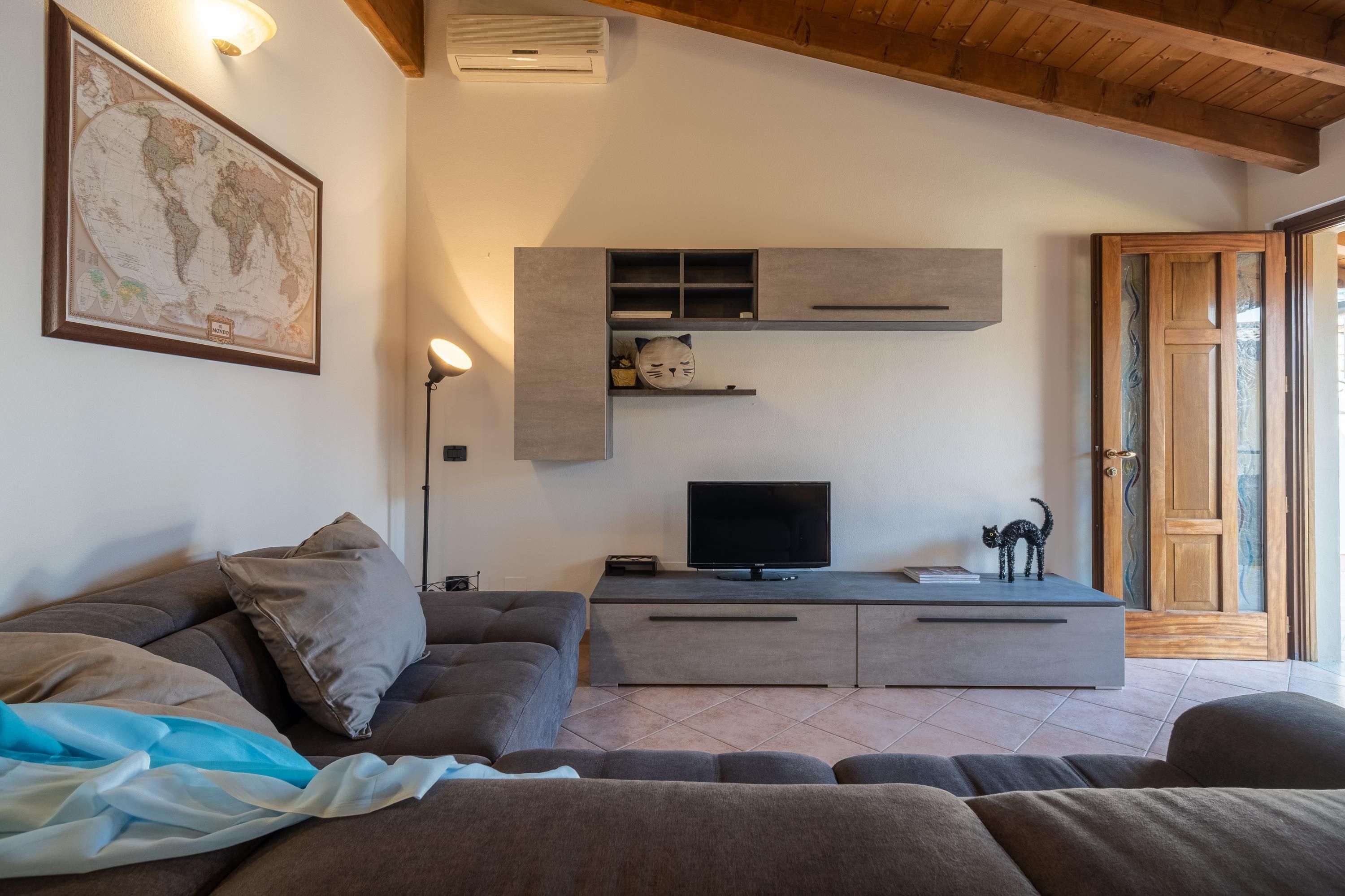 A modern living room with a grey sofa, a flat-screen TV, and a world map on the wall.