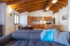 Een moderne keuken met houten kastjes en een zithoek met een bank.