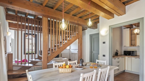 Ein Essbereich mit einem Holztisch, weißen Stühlen und einer Treppe, die auf einen Balkon führt.
