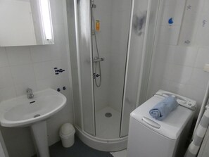 Ein Badezimmer mit Dusche, Waschbecken und einer kleinen Waschmaschine.