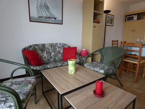 Ein gemütlicher Wohnbereich mit einer Couch, zwei Sesseln, einem Tisch, einer Lampe und einem gerahmten Bild an der Wand.