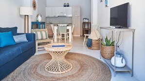 A modern living room with a blue sofa, a round wicker coffee table, and a TV on a white stand. - Cala Moresca in Golfo Aranci (Golfo Aranci)