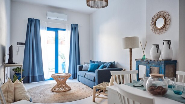 A modern living room with a sofa, a dining table with chairs, a wicker coffee table, and a lamp. - Cala Moresca in Golfo Aranci (Golfo Aranci)