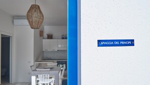 A modern kitchen with white cabinets and a hanging light fixture. - Spiaggia del Principe (Arzachena)
