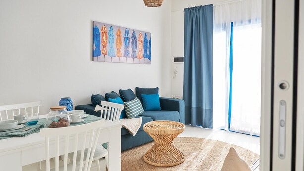 A modern living room with a sofa, a dining table with chairs, a coffee table, and a painting on the wall. - Spiaggia del Principe (Arzachena)