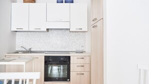 A modern kitchen with white cabinets, a black oven, and a tiled backsplash. - Spiaggia del Principe (Arzachena)