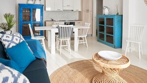 A modern kitchen with white cabinets, a dining area with white chairs, and a blue cabinet with glass doors.